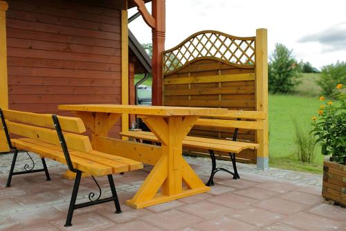 a wooden picnic table and two benches on a patio at Wakacje w Radziuciach in Sejny