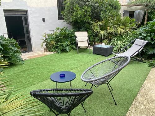 une cour avec une pelouse, deux chaises et une table dans l'établissement Les Lauriers Duplex centre ville avec jardin, à Nyons