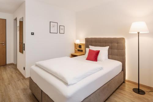 a bedroom with a large white bed with a red pillow at Hotel Obermaier in Munich