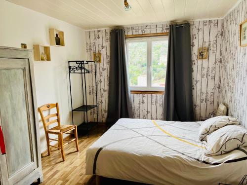 une chambre avec un lit, une fenêtre et une chaise dans l'établissement Le domaine des Oliviers ALES Piscine Jacuzzi Sauna, à Alès