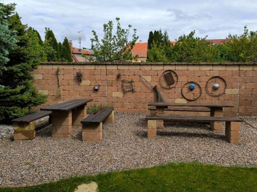 a picnic table and benches in front of a brick wall at Ubytování U Janča in Lednice