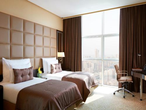 a hotel room with two beds and a window at Millennium Hotel & Convention Centre Kuwait in Kuwait