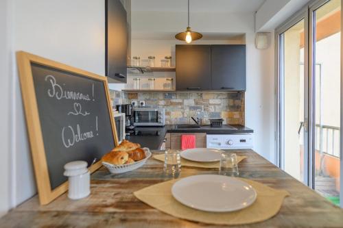 a kitchen with a table with plates and a chalkboard at Côté Sud in Palavas-les-Flots