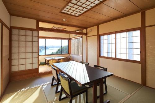 Habitación con mesa, sillas y ventanas. en Villa Ryusei en Ugata