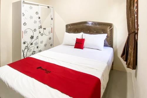 a bedroom with a bed with a red blanket on it at RedDoorz Near Batu Ampar Harbour in Jodoh
