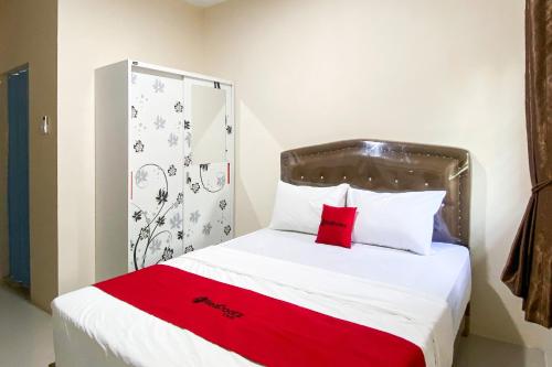 a bedroom with a bed with a red blanket on it at RedDoorz Near Batu Ampar Harbour in Jodoh