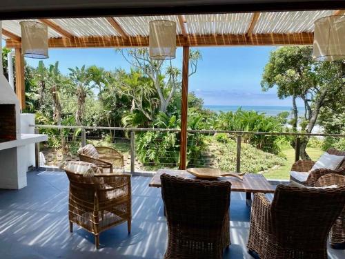 un patio con mesa y sillas y vistas al océano en Woodlands Beach Villa en Southbroom