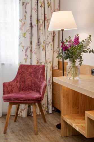 a red chair sitting next to a table with a vase of flowers at Hotel Obermaier in Munich