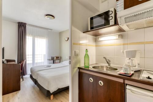 une chambre d'hôtel avec un lit et un lavabo dans l'établissement Zenitude Hôtel-Résidences Béziers Centre, à Béziers