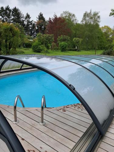 una piscina con techo de cristal en una terraza de madera en Le buisson de la Gariole, en Aubigny-sur-Nère