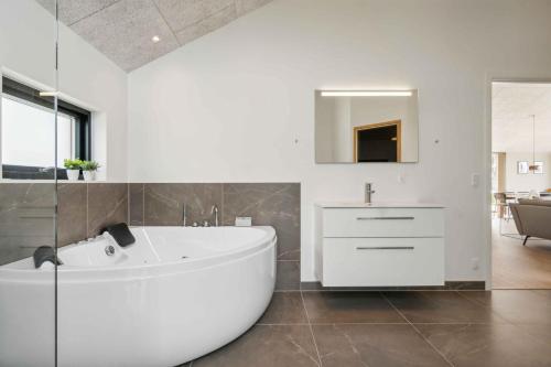 La salle de bains blanche est pourvue d'une baignoire et d'un lavabo. dans l'établissement Impressive Holiday Cottage, By The Helsns Bay!, à Millinge