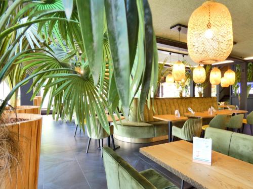 un restaurant avec des tables et des chaises en bois et des plantes dans l'établissement Contact Hotel Be Guest Limoges Sud, à Limoges