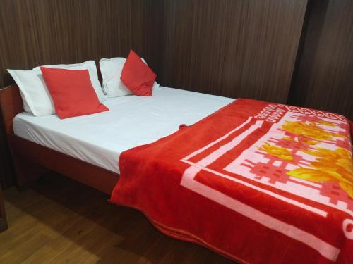 a bed with a red and white blanket on it at Misty Meadows in Ooty