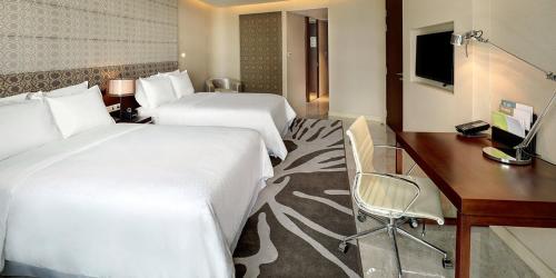 a hotel room with two beds and a desk at Crowne Plaza Dhaka Gulshan by IHG in Dhaka