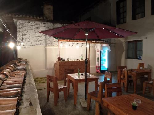 Te MuzzeU Hostel في بيرات: مطعم بطاولات وكراسي ومظلة