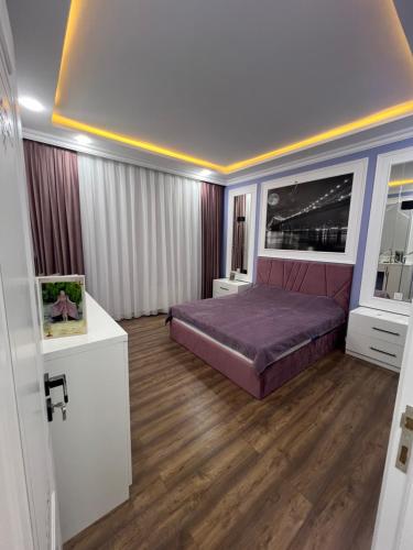 a bedroom with a purple bed and wooden floors at My_willa_Buzovna in Zağulba Bağları