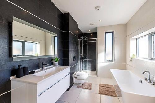 y baño con bañera, aseo y lavamanos. en 2 Bedroom Penthouse in Brentford, en Brentford
