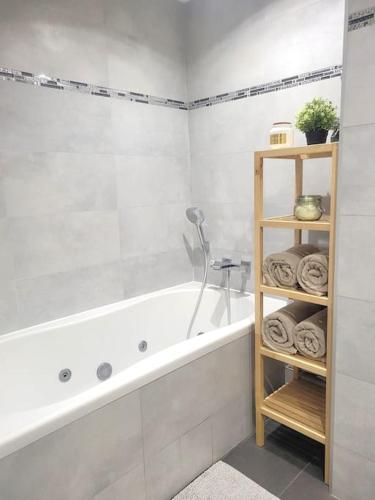 La salle de bains est pourvue d'une baignoire et d'une étagère avec des serviettes. dans l'établissement Appartement moderne 2 chambres, à Saint-Maurice