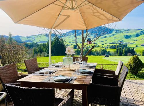 a wooden table with an umbrella on a patio at Chalet - Kleines Paradies - in Appenzell