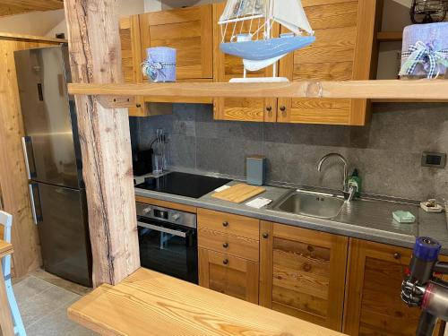 eine Küche mit Holzschränken und einer Spüle aus Edelstahl in der Unterkunft monolocale incantevole in Sordevolo