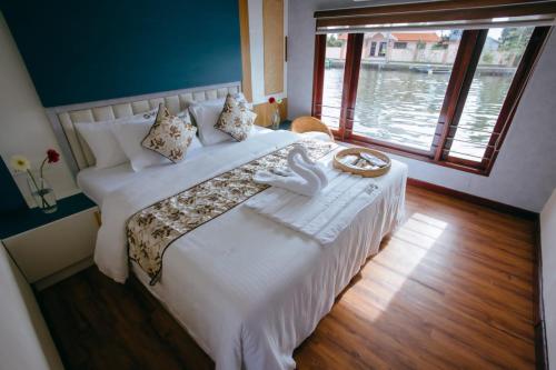 a bedroom with a large white bed with a large window at Boats N Beds in Alleppey