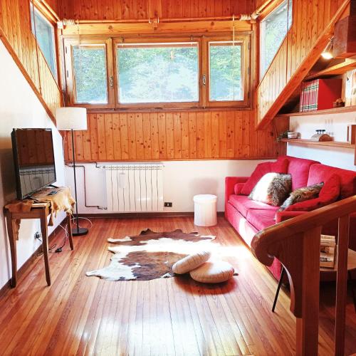 a living room with a red couch on a wooden floor at Quick Home - Viola in Pontboset