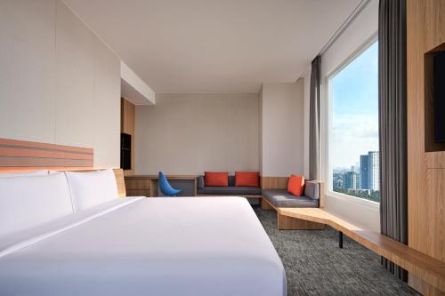 a hotel room with a bed and a large window at Aloft South Jakarta in Jakarta