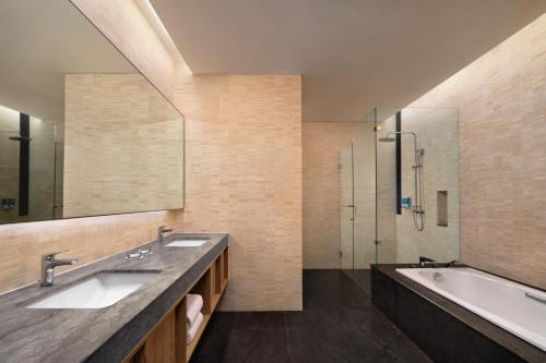 a bathroom with two sinks and a tub and a shower at Aloft South Jakarta in Jakarta