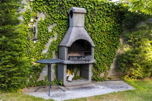 a stone oven with a stool in a garden at Casa Luxury Wellness Apartman By BLTN in Siófok