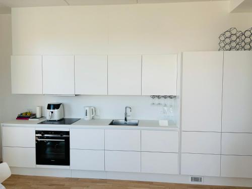 una cocina blanca con armarios blancos y fregadero en View from the 18th floor over whole of Copenhagen. en Copenhague