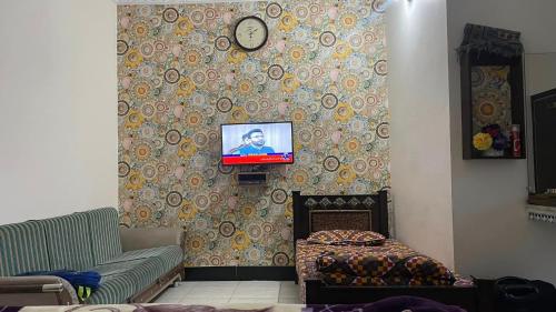 a living room with a couch and a tv on a wall at Red Rose Hotel in Bālākot