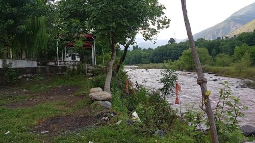 a river with rocks and trees next to a river at Red Rose Hotel in Bālākot