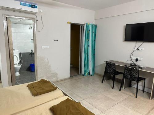um quarto com uma cama, uma secretária e uma televisão em POP 82272C Townhouse Oak- Seven Olives em Bangalore