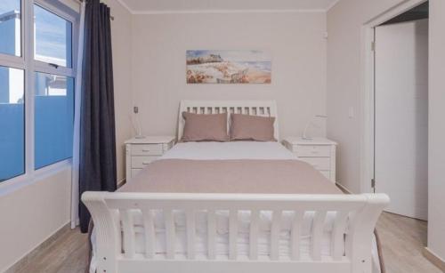 a white bedroom with a white bed and a window at Fellowship in Agulhas