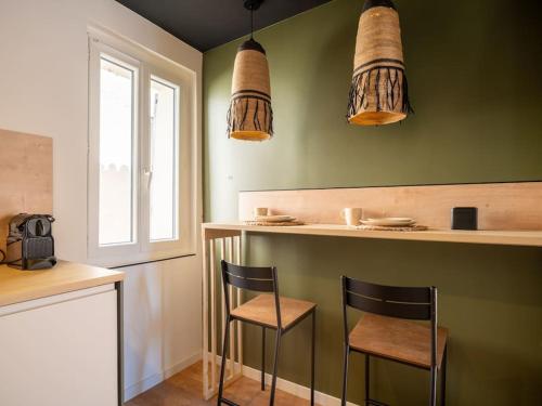 une cuisine avec deux chaises dans un bar aux murs verts dans l'établissement Le Bocage - Studio 2 couchages - Centre Historique, à Aubagne