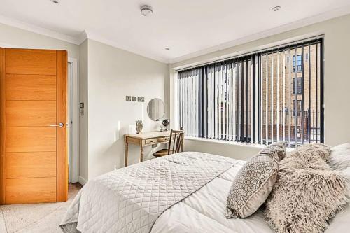 een slaapkamer met een bed en een raam met een bureau bij Modern Chic and Contemporary Retreat in Brentford in Brentford