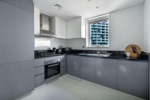 uma cozinha com armários cinzentos e uma janela em GuestReady - Relaxing retreat in Business Bay em Dubai