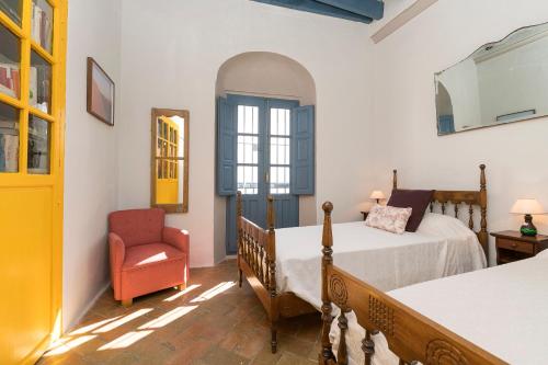 1 dormitorio con 2 camas y 1 silla en Casa Marina - Centro Histórico en Vejer de la Frontera