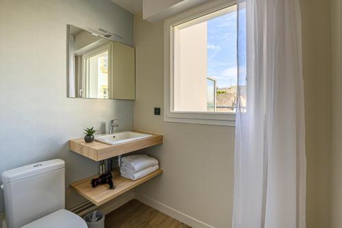 La salle de bains est pourvue de toilettes, d'un lavabo et d'une fenêtre. dans l'établissement Appart Hôtel Le Liberté Vannes Centre-Ville, à Vannes