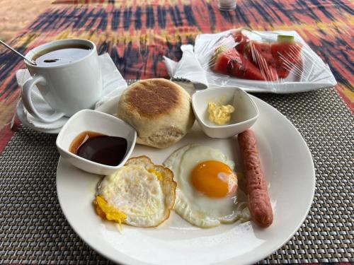 a plate of breakfast food with eggs sausage and a cup of coffee at Janibichi Adventures hostel in Moshi