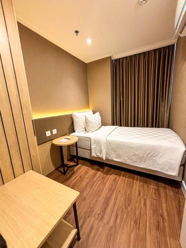 a small hotel room with a bed and a window at Swiss-Belcourt Serpong in Ciater-tengah