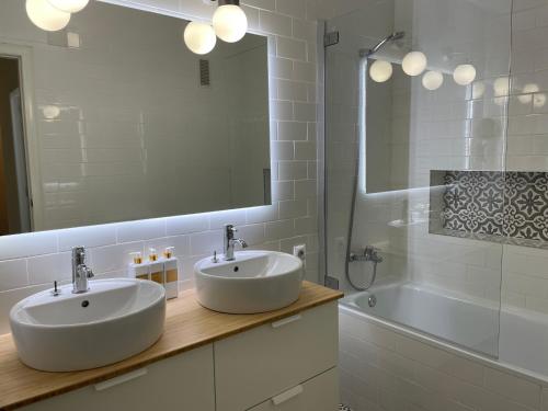 een badkamer met 2 wastafels, een spiegel en een bad bij EPIS - large luxury apartment with sea view in Benicàssim