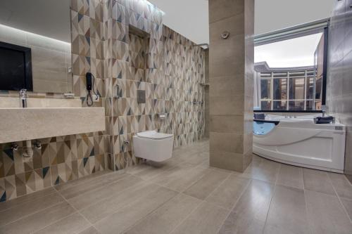 ِAluya Hotel في جدة: حمام مع مرحاض ومغسلة وحوض استحمام