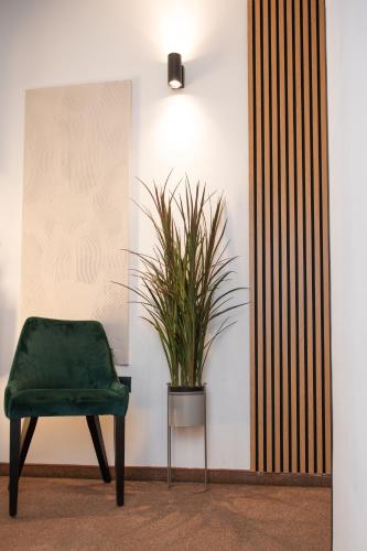 a green chair and a potted plant in a room at Hotel Marina in Fažana