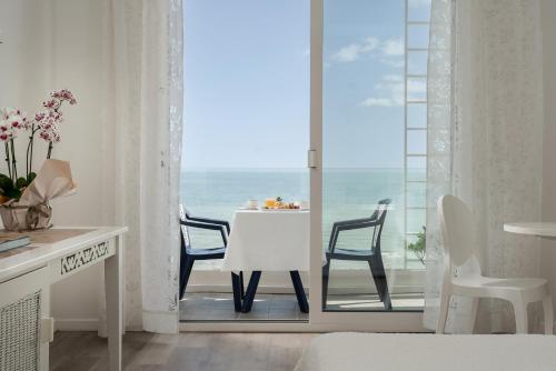 a room with a table and chairs and a view of the ocean at Hotel Mediterraneo in Riccione