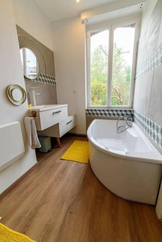 La salle de bains est pourvue d'une baignoire blanche et d'une fenêtre. dans l'établissement Le 304 Douai, à Douai