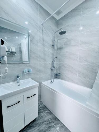 uma casa de banho branca com uma banheira e um lavatório em Hotel Bereket Karaganda em Karaganda