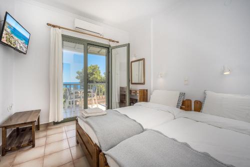a bedroom with two beds and a window with a view at 123 Soleil Studios in Agia Marina Aegina