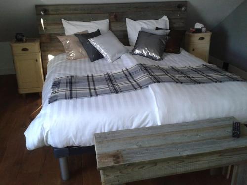 uma cama grande com lençóis brancos e almofadas em Riante Boerderij in Het Groene Hart Regio Utrecht em Oudewater