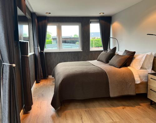 a bedroom with a large bed and two windows at Bed and Breakfast Roodkapje in Kaatsheuvel